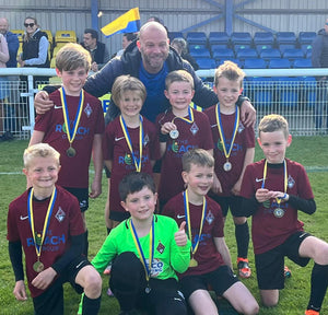 Coach with youth boys team kneeling with their medals